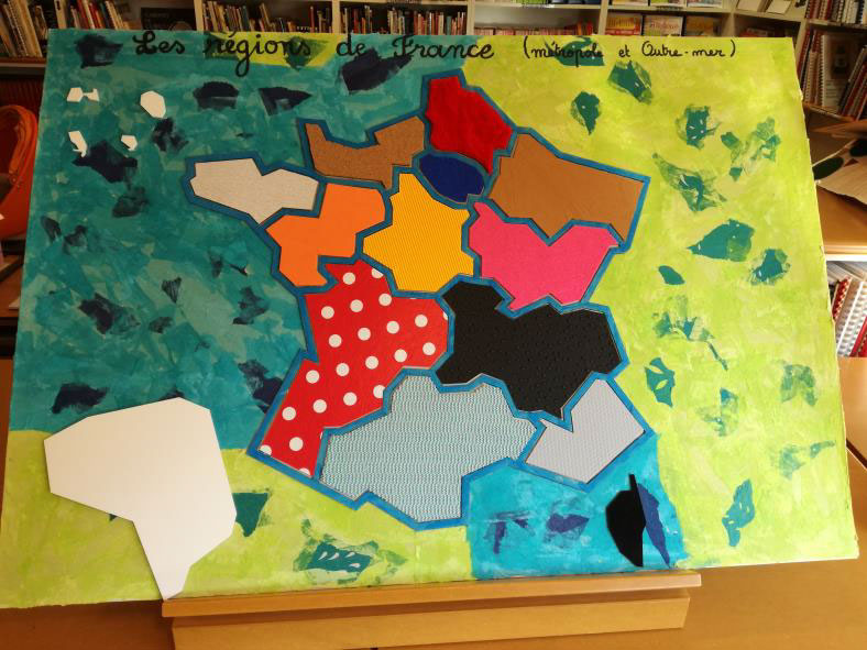 Photo d'une carte de France des régions. Les régions sont délimitées par un contour en carton. Chaque région est représentée par une texture différente : cuir, toile cirée, tissu, feutrine, carton granuleux... Les couleurs sont également variées.
