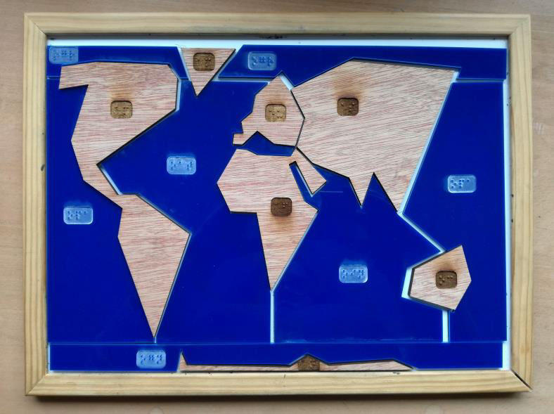 photo d'un puzzle planisphère découpé ultra simplifié, avec les continents en bois et les océans en plexiglas bleu.
